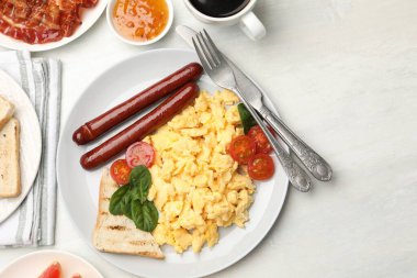 Lezzetli bir kahvaltı. Hafif ahşap masada servis edilen sosis ve domatesli nefis çırpılmış yumurta. Metin için boşluk