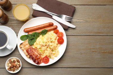 Lezzetli bir kahvaltı. Tahta masada servis edilen domuz pastırmalı, sosisli ve domatesli nefis çırpılmış yumurta. Metin için boşluk