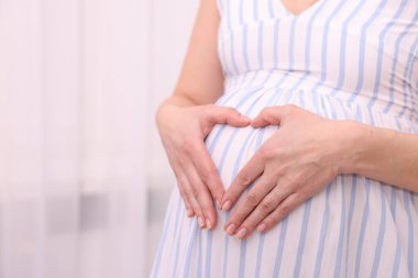 Hamile kadın karnının yanında kalp hareketi yapıyor. Kapalı.