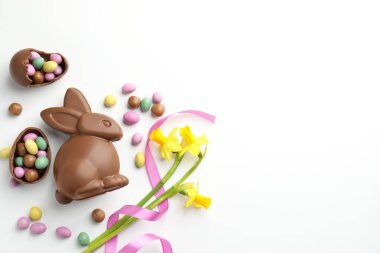 Çikolatalı Paskalya tavşanı, çiçekler, beyaz arka planda kurdele ve yumurtalar, düz yatak. Metin için boşluk