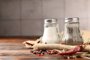 Ahşap masada baharatlı tuzluk ve biberlikler, yakın plan. Metin için boşluk