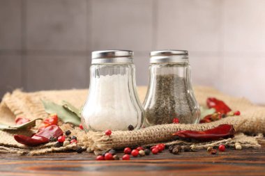 Ahşap masada baharatlı tuzluk ve biberlikler, yakın plan.