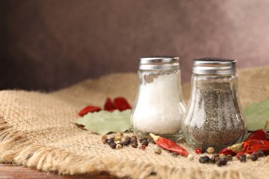 Ahşap masada baharatlı tuzluk ve biberlikler, yakın plan. Metin için boşluk