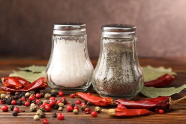 Ahşap masada baharatlı tuzluk ve biberlikler, yakın plan.