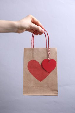 Arka planda kalbi açık bir hediye çantası taşıyan bir kadın, yakın plan. Sevgililer Günü