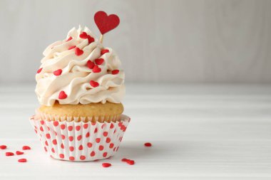 Sevgililer Günün kutlu olsun. Gri duvarın yanındaki beyaz ahşap masada kalp şeklinde serpiştirilmiş lezzetli kek, yakın plan. Metin için boşluk