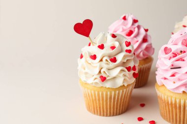 Sevgililer Günün kutlu olsun. Açık gri arka planda kalp şeklinde serpiştirilmiş lezzetli kapkekler, yakın plan. Metin için boşluk