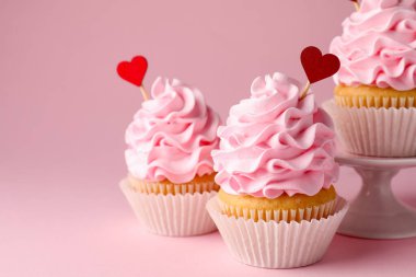 Sevgililer Günün kutlu olsun. Pembe arka planda kırmızı kalp kaplamalı lezzetli kekler, yakın plan. Metin için boşluk