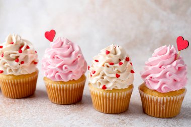 Sevgililer Günün kutlu olsun. Gri masada kırmızı kalpli lezzetli kekler, yakın plan.