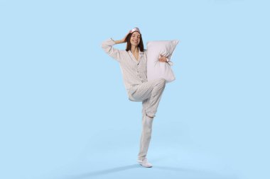 Maske takan güzel bir kadın ve açık mavi arka planda yastıklı şık pijamalar.