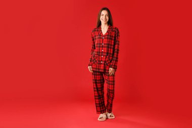 Kırmızı arka planda şık pijamalı mutlu kadın, mesaj için yer var.