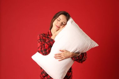 Kırmızı arka planda yastıklı şık pijamalı bir kadın.