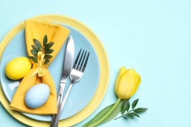 Paskalya kutlaması. Lale çiçekli şenlik masası, yeşil yapraklar ve açık mavi arka planda boyanmış yumurtalar. Metin için boşluk