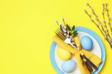 Paskalya kutlaması. Söğüt dalları ve sarı arka planda boyanmış yumurtalarla süslü masa ayarları, düz yatış. Metin için boşluk
