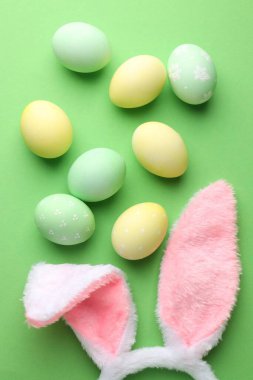 Mutlu Paskalyalar. Şirin tavşan kulakları ve yeşil arka planda boyanmış yumurtalar.