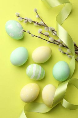Boyalı Paskalya yumurtaları, söğüt dalları ve açık yeşil arka planda kurdele.