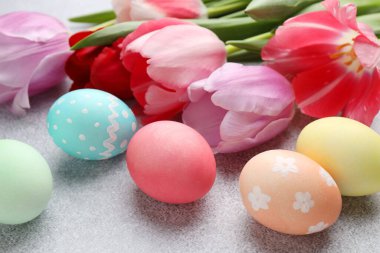 Boyanmış Paskalya yumurtaları ve gri desenli masada güzel laleler. Yakın plan.