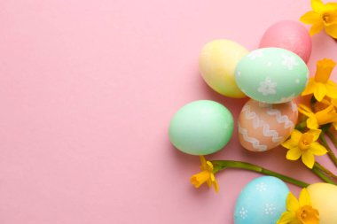 Paskalya yumurtaları ve pembe arka planda güzel nergisler, düz yatak. Metin için boşluk