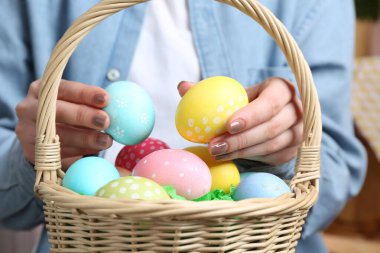 Paskalya sepetinde yumurta boyalı bir kadın, kapalı bir masada, yakın plan.