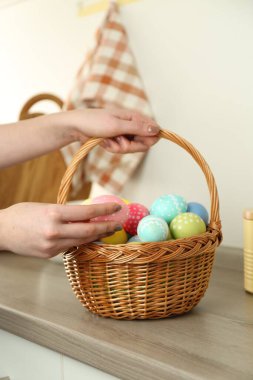 Paskalya sepetinde boyanmış yumurtalı bir kadın, kapalı masa, yakın plan.