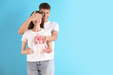Sevgililer Günü. Mutlu genç adam kız arkadaşına sürpriz yapıyor açık mavi arka planda, mesaj için yer var.