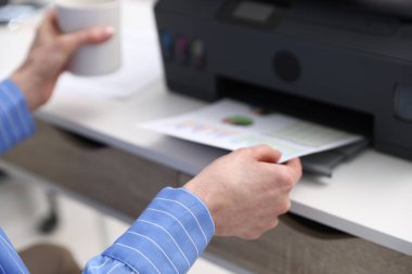 Beyaz masadaki yazıcıdan baskı kağıdı alan kadın, yakın plan.