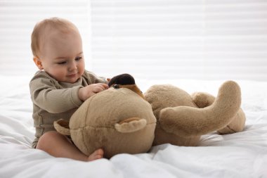 Evde yatağında oyuncak ayıyla sevimli bir bebek.