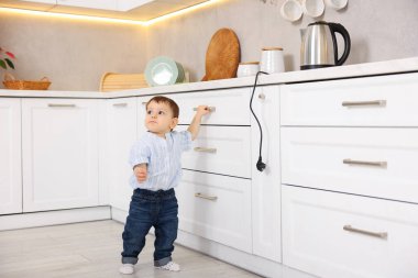 Evde çocuk güvenliği. Küçük çocuk mutfakta elektrikli su ısıtıcısına uzanıyor.