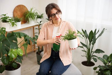 Güzel saksı bitkisine su püskürten bir kadın.