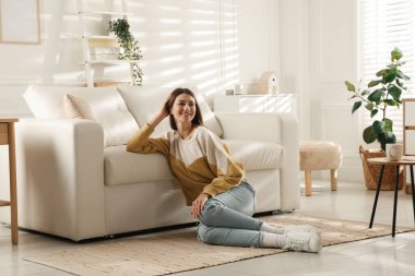 Evdeki koltuğun yanında dinlenen bir kadın.