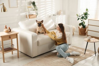 Evdeki kanepenin yanında tatlı köpeği olan bir kadın.