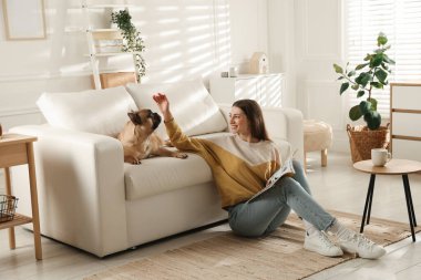 Evdeki kanepenin yanında tatlı köpeği olan bir kadın.