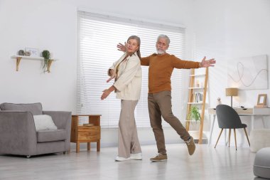 Mutlu yaşlı çift evde dans ediyor.
