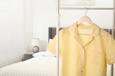 İçerideki yatağın yanındaki askıda asılı şık pijama gömleği, yakın plan. Metin için boşluk