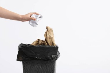 Beyaz arka plandaki çöp kutusuna kağıt atan kadın, yakın plan. Metin için boşluk