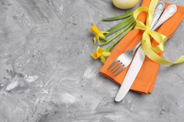 Paskalya sofrası. Gri desenli arka planda nergisleri olan güzel gümüş takımlar. Metin için boşluk