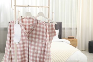 Şık pijamalar ve uyku maskesi yatağın yanındaki rafta asılı, yakın plan.