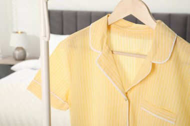 Yatağın yanındaki askıda asılı şık pijama gömleği, yakın plan.