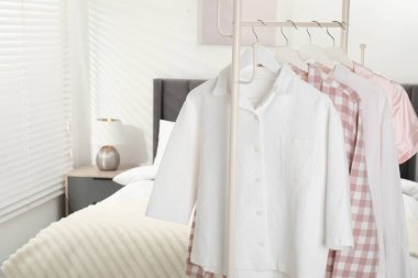 İçerideki yatağın yanındaki askıda asılı şık pijama gömlekler, yakın plan. Metin için boşluk
