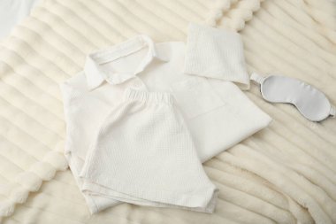 Yatağın üstünde şık pijamalar ve uyku maskesi.