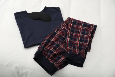 Yatağın üstünde şık pijamalar ve uyku maskesi.