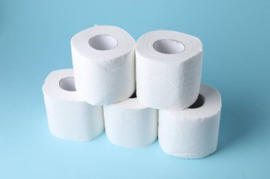 Açık mavi arkaplanda tuvalet kağıdı ruloları, yakın plan