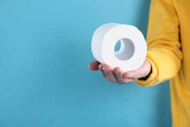 Açık mavi arka planda tuvalet kağıdı rulosu olan adam, yakın plan. Metin için boşluk