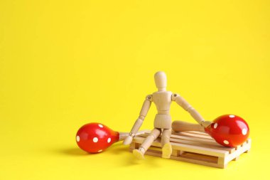 Sarı arka planda oyuncak marakas olan tahta mankenler, yakın plan. Metin için boşluk
