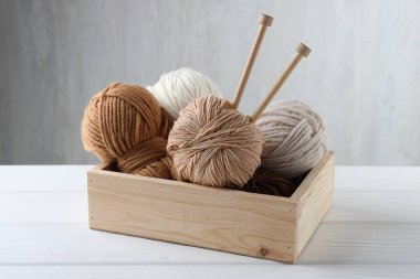 Örgü iplikleri ve iğneler beyaz ahşap masada, yakın plan.