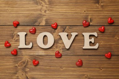 Sözcük Aşk harflerden ve kırmızı kalplerden yapılmıştır ahşap masada, düz yatar