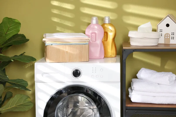 Çamaşır sepetinin içinde çamaşır makinesinin üzerinde katlanmış temiz kıyafetler var.