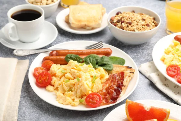 Lezzetli bir kahvaltı. Lezzetli omlet, pastırma, sosis ve domates. Gri desenli masada servis ediliyor. Yakın plan.