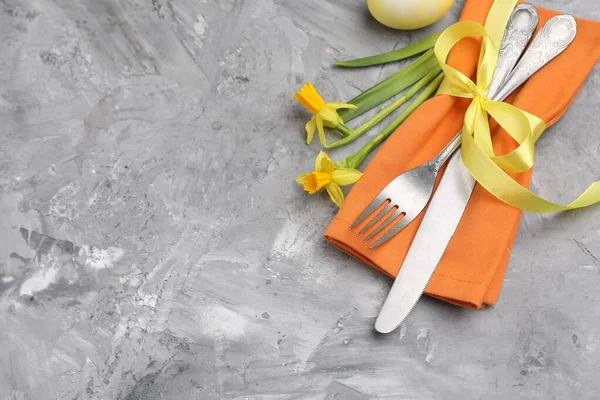 Paskalya sofrası. Gri desenli arka planda nergisleri olan güzel gümüş takımlar. Metin için boşluk