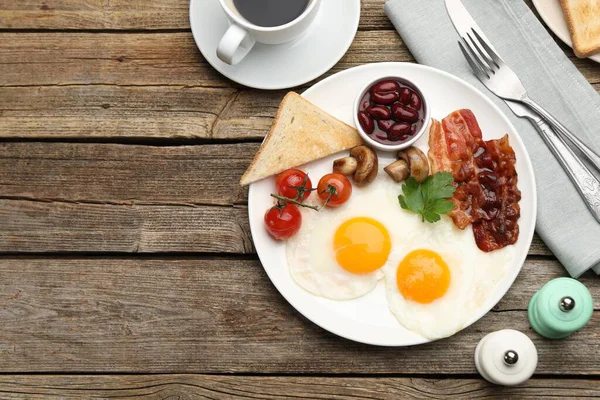 Geleneksel İngiliz kahvaltısı. Pastırmalı, fasulyeli, domatesli, mantarlı ve ahşap masada servis edilen kızarmış ekmekli nefis, güneşli yumurtalar. Metin için boşluk
